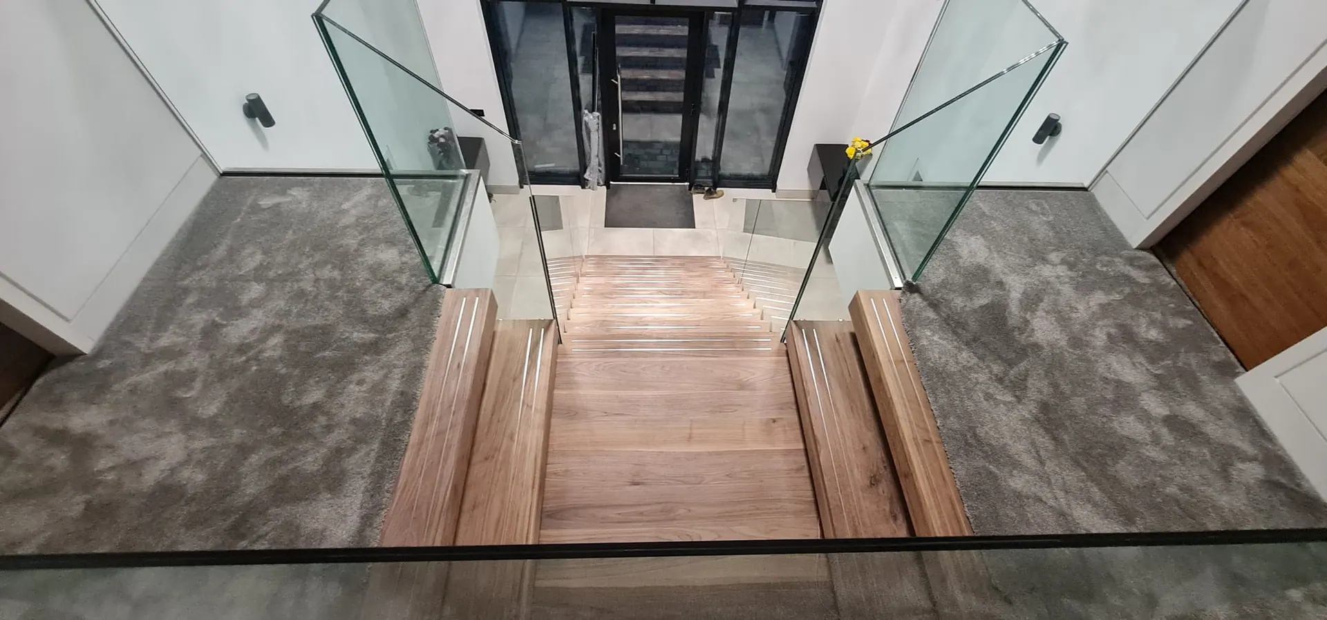 Floating walnut treads between frameless glass balustrades