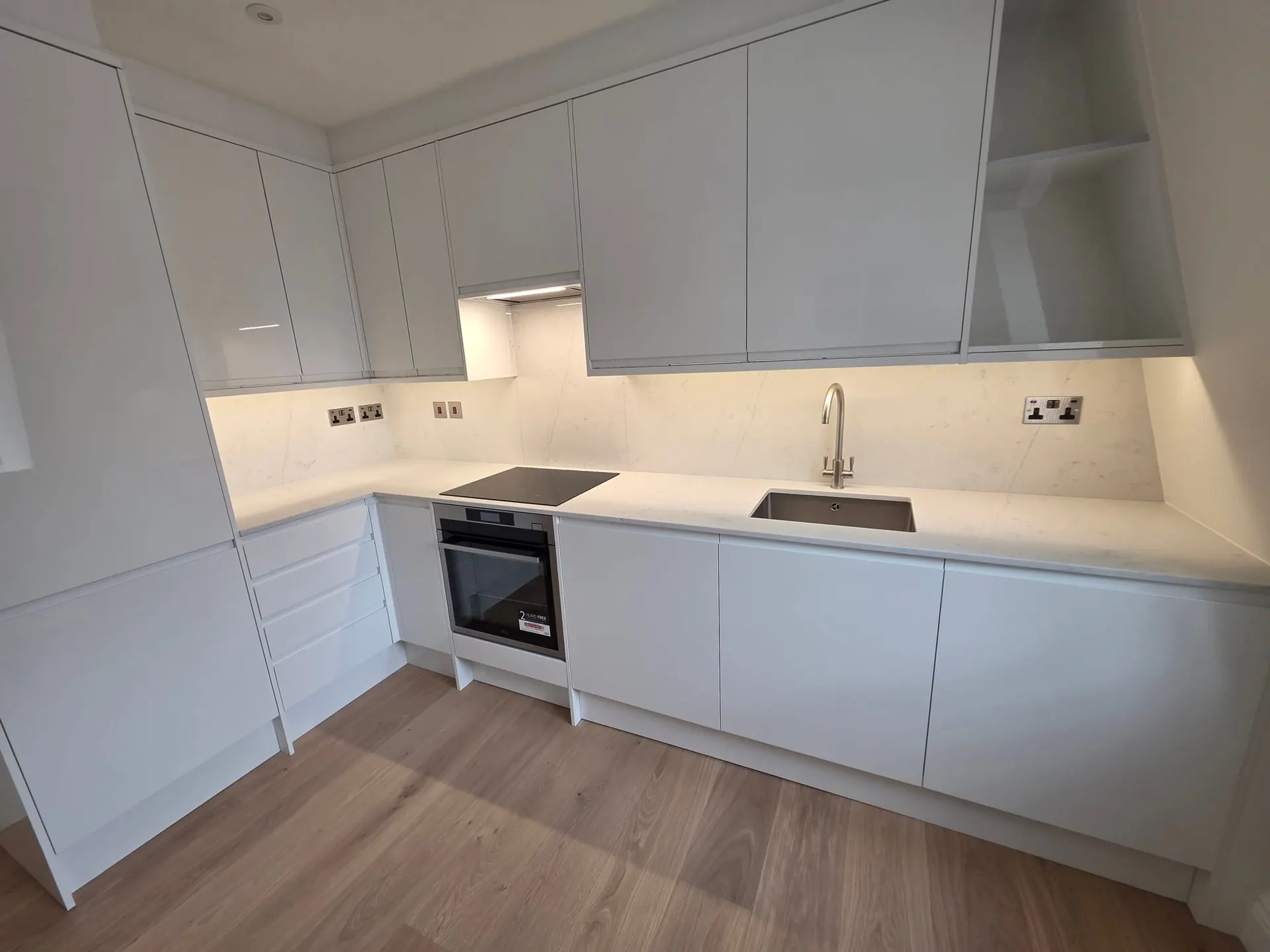 White handleless kitchen with quartz worktops and under-cabinet lighting